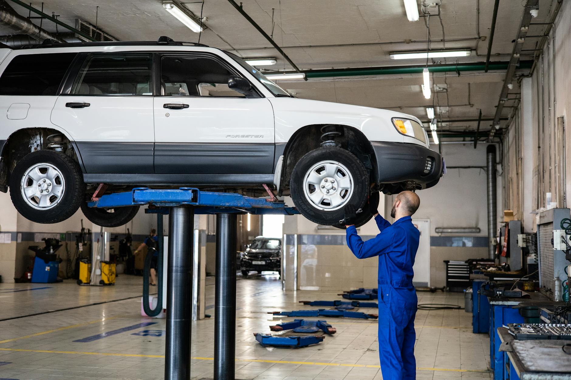 Mechanik ogląda białego SUV-a Peugeota na podnośniku w warsztacie