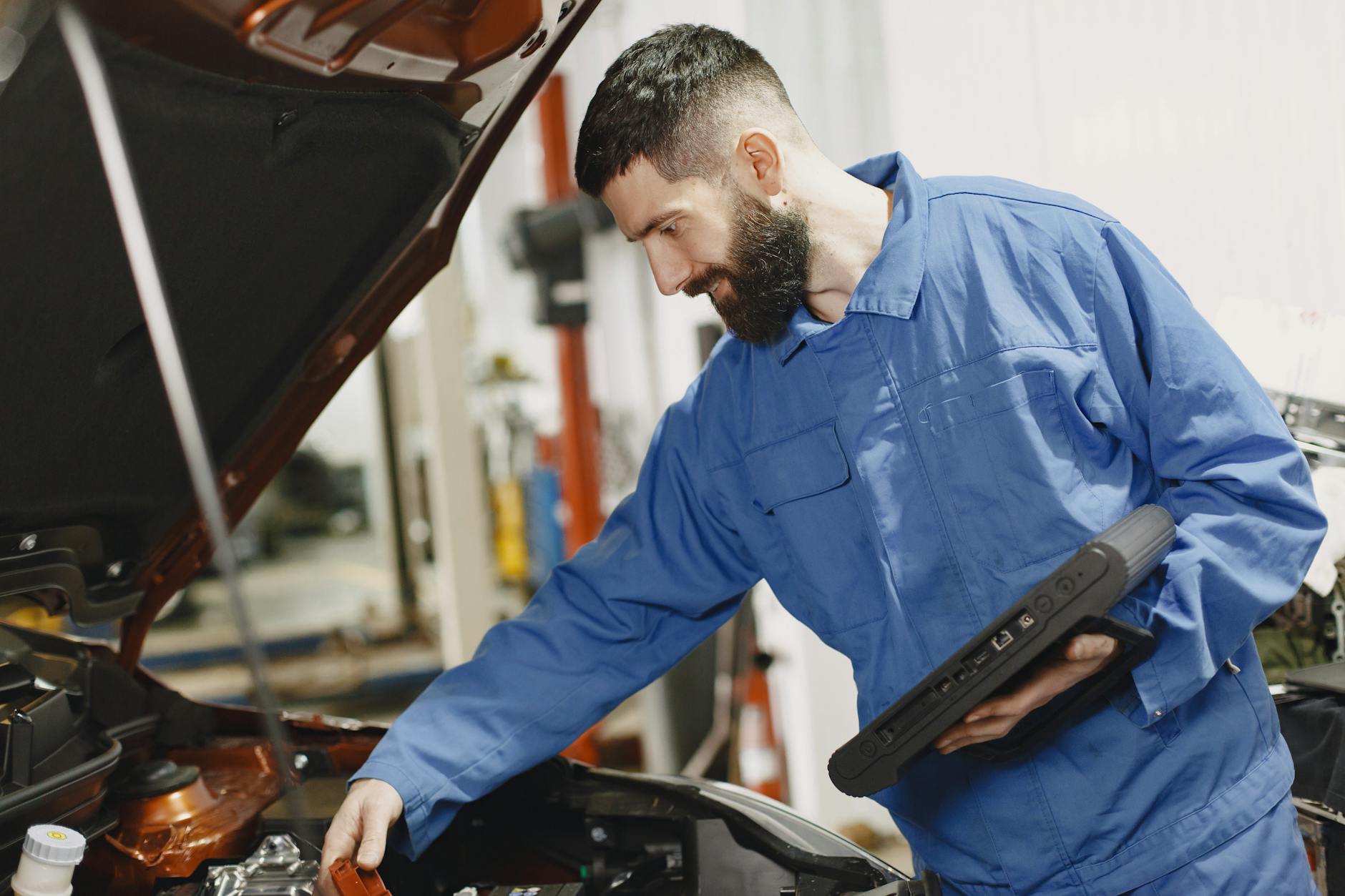 Najczęstsze błędy przy zakupie używanego Peugeota: jak czytać historię serwisową i rozpoznać cofnięty licznik Mechanik w niebieskim kombinezonie sprawdza silnik samochodu w warsztacie