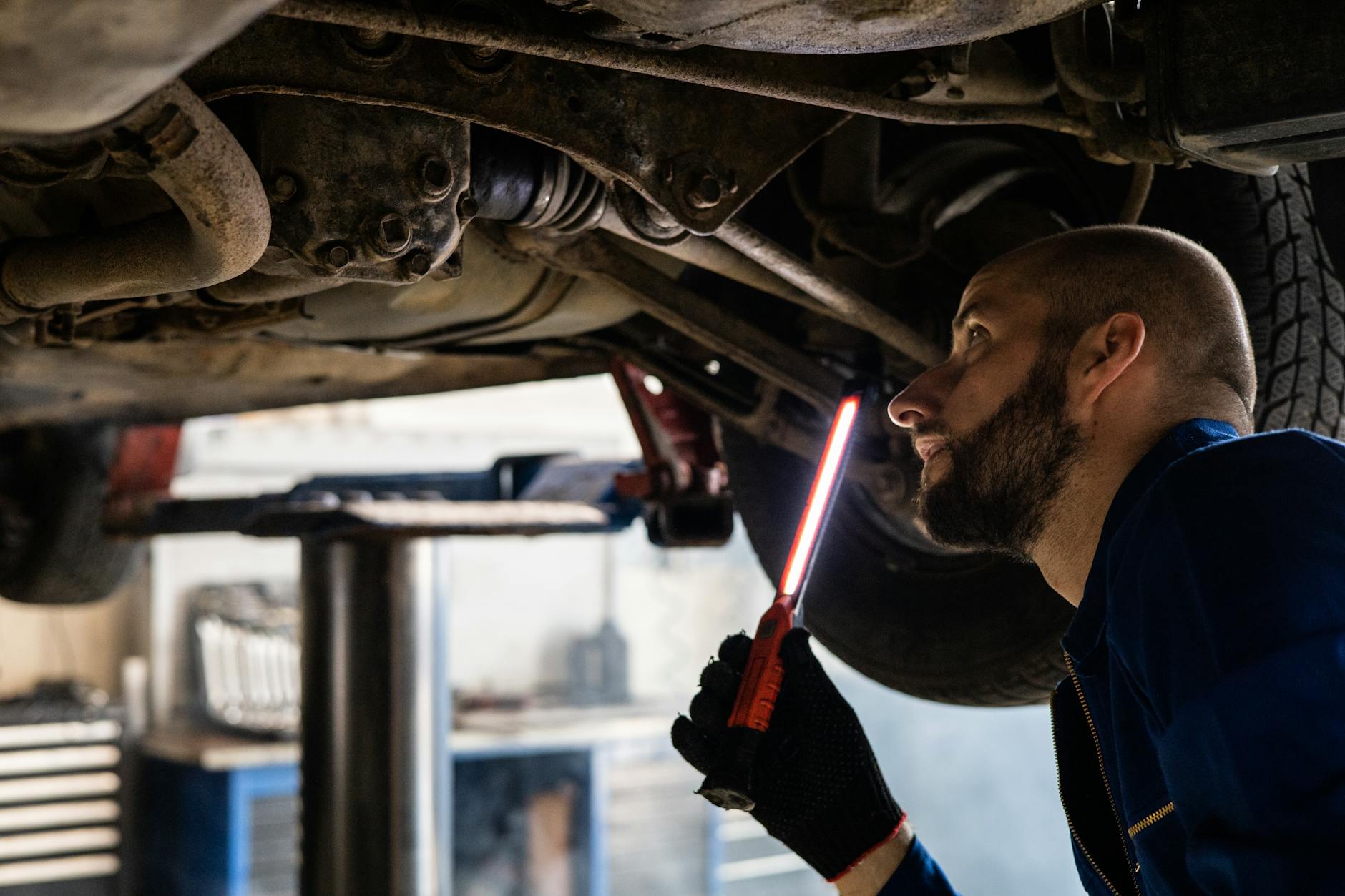 Mechanik z lampą kontroluje podwozie samochodu w warsztacie
