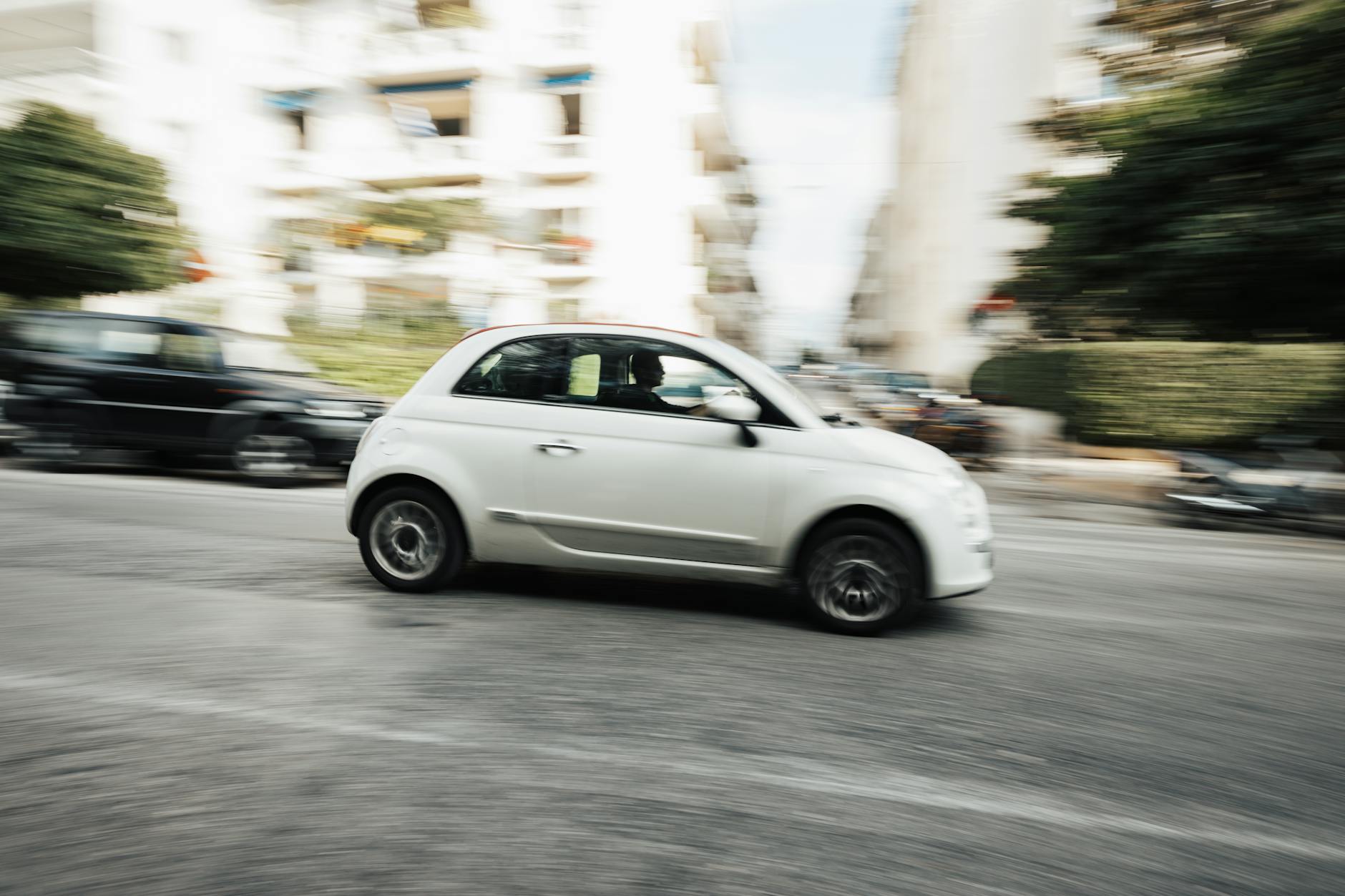 Białe miejskie auto Suzuki Swift pędzące ulicą w ruchu miejskim