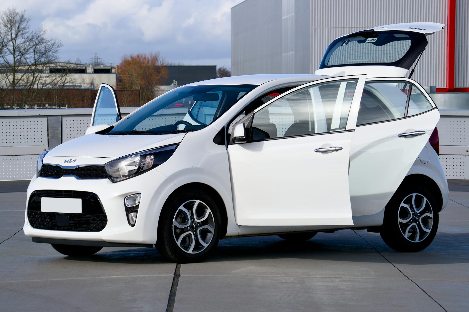 Biały kompaktowy Nissan z otwartymi drzwiami na miejskiej ulicy