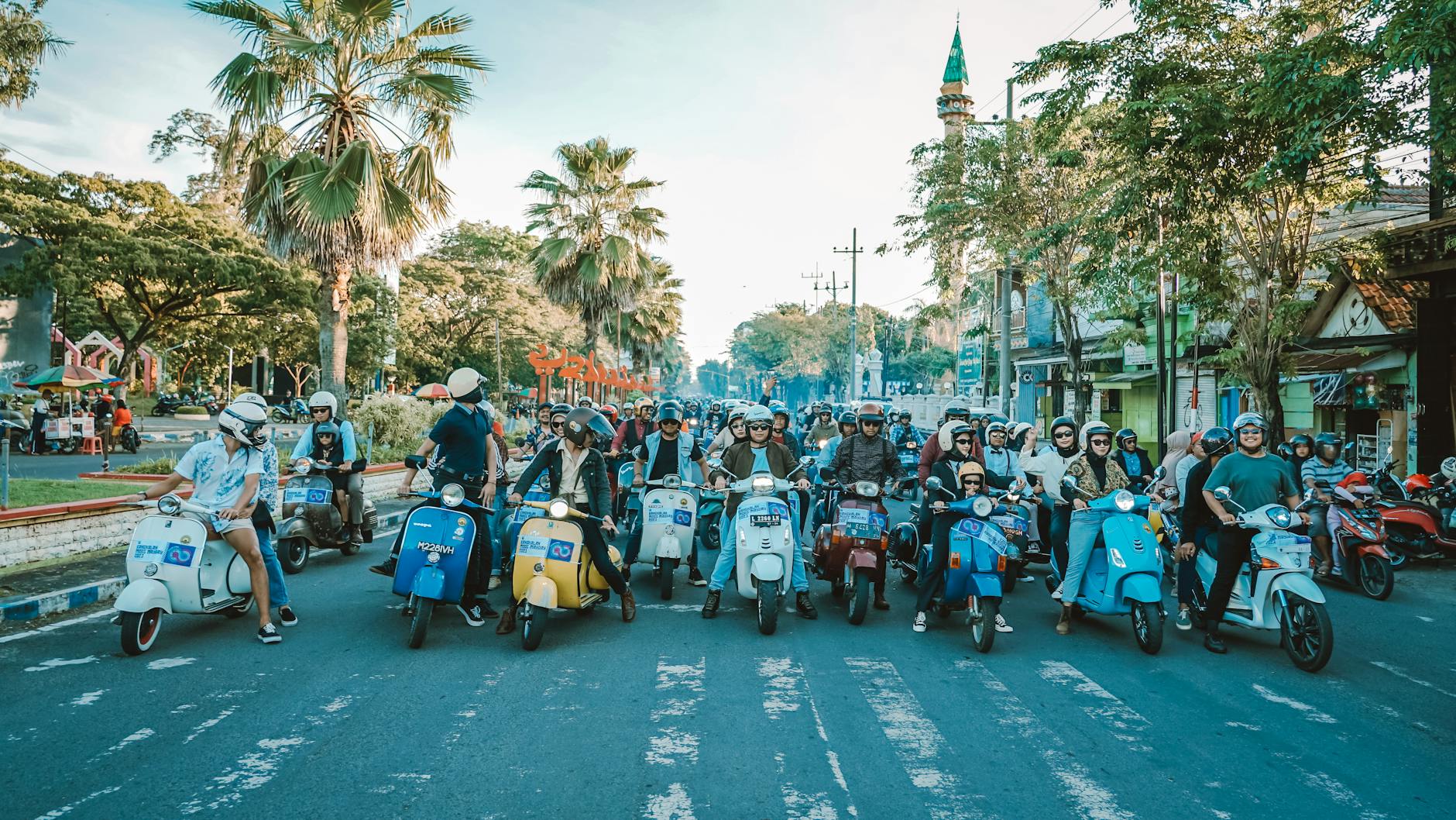 Grupa dorosłych na skuterach Vespa jedzie wspólnie w tropikalnym słońcu