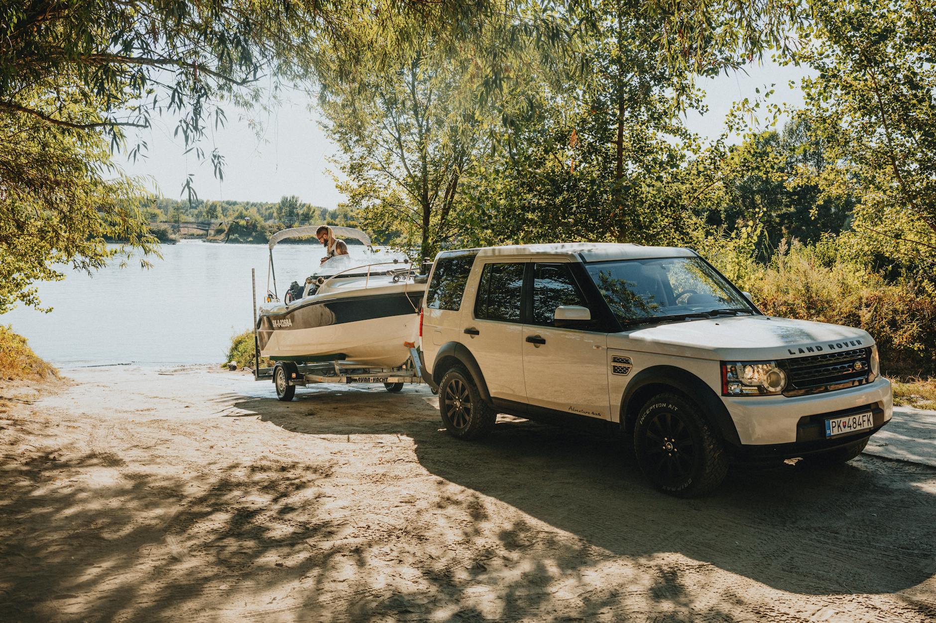 Land Rover z przyczepą i łodzią nad jeziorem w słoneczny dzień