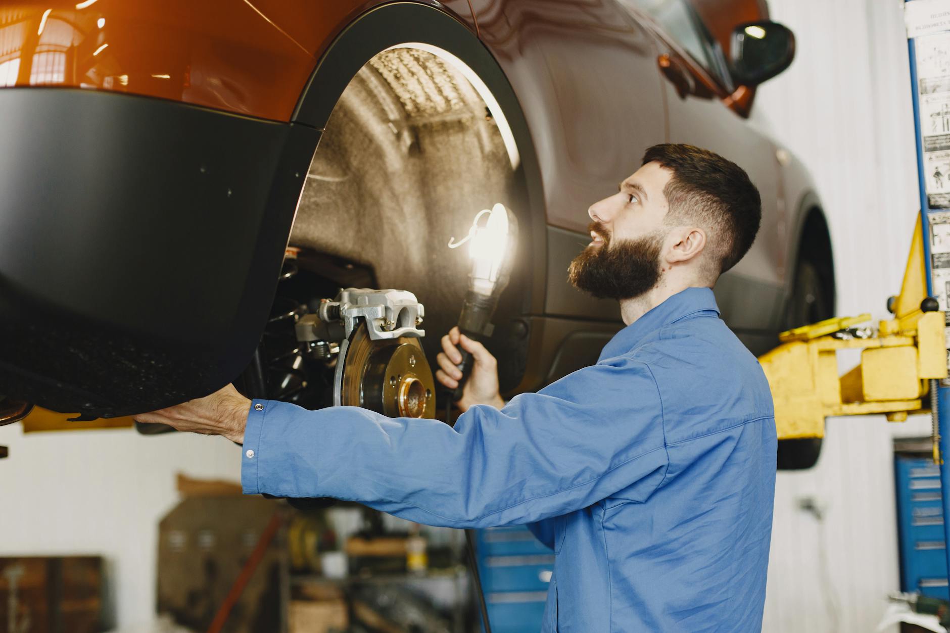 Mechanik w niebieskim kombinezonie sprawdza hamulce w serwisie Hondy