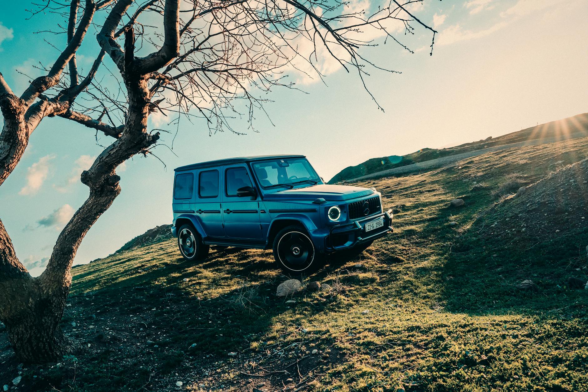 Niebieski Mercedes G klasa na wzgórzu w słoneczny dzień