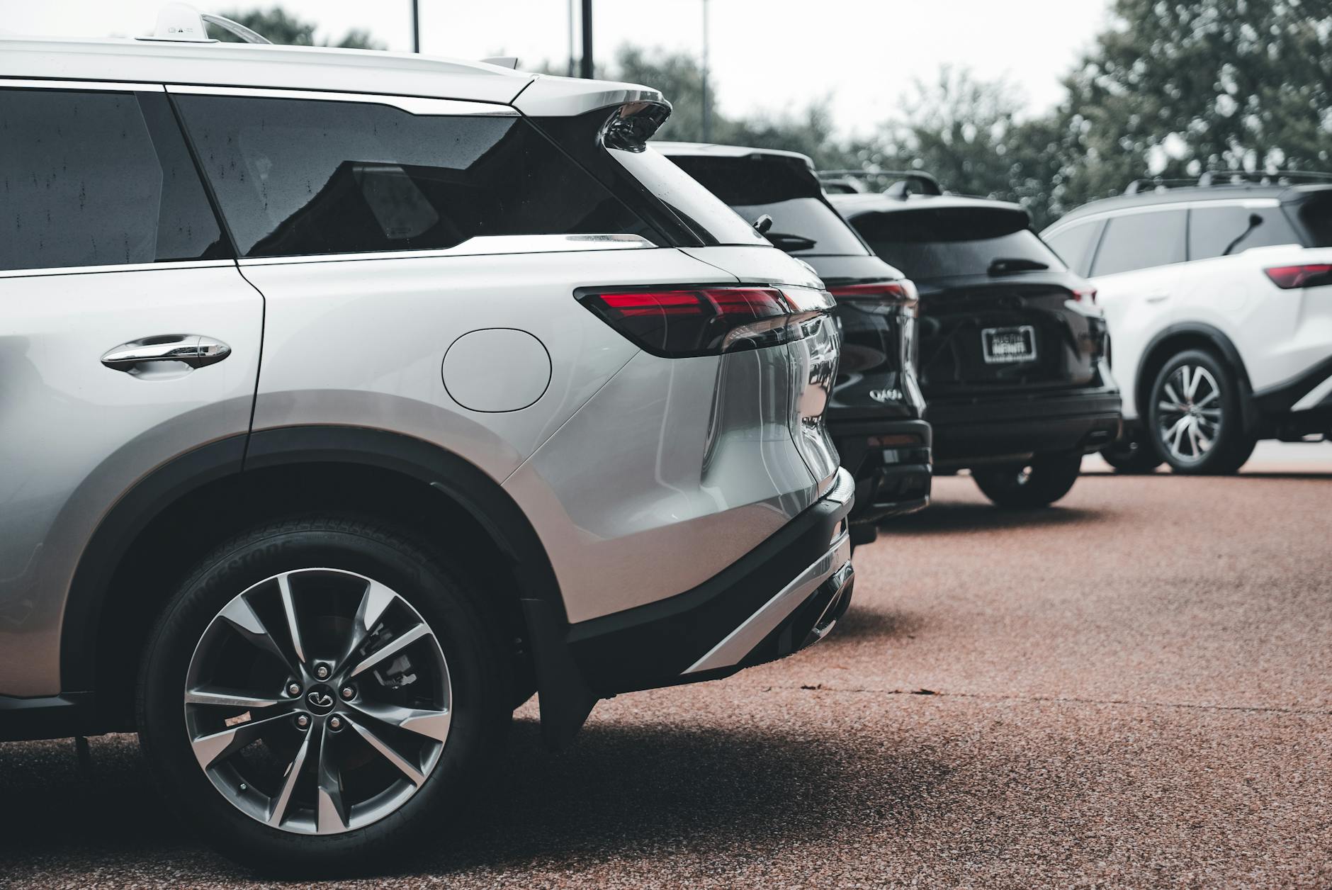 Srebrne SUV-y zaparkowane w rzędzie na otwartym parkingu