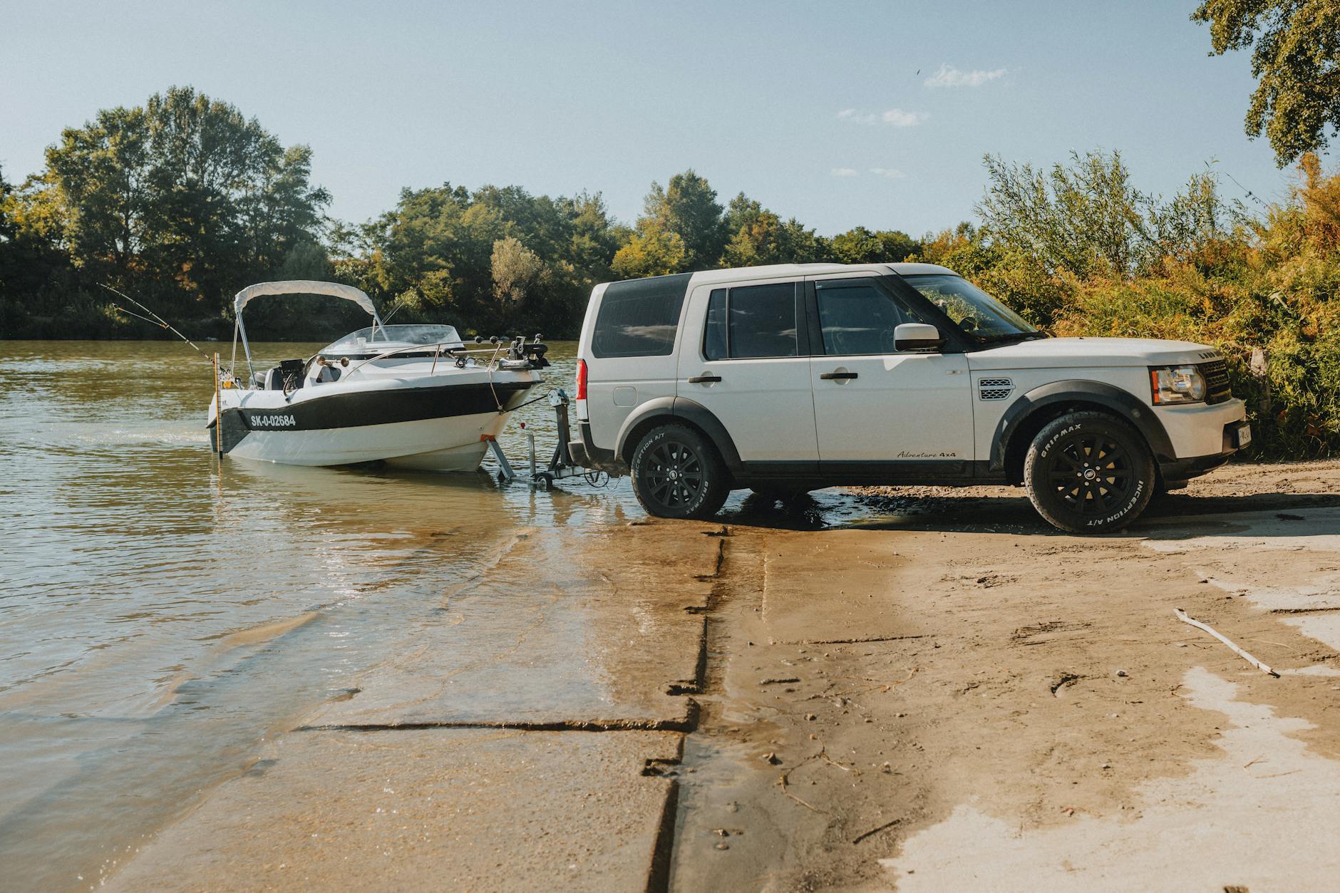SUV z przyczepą wodującą motorówkę do rzeki w słoneczny dzień