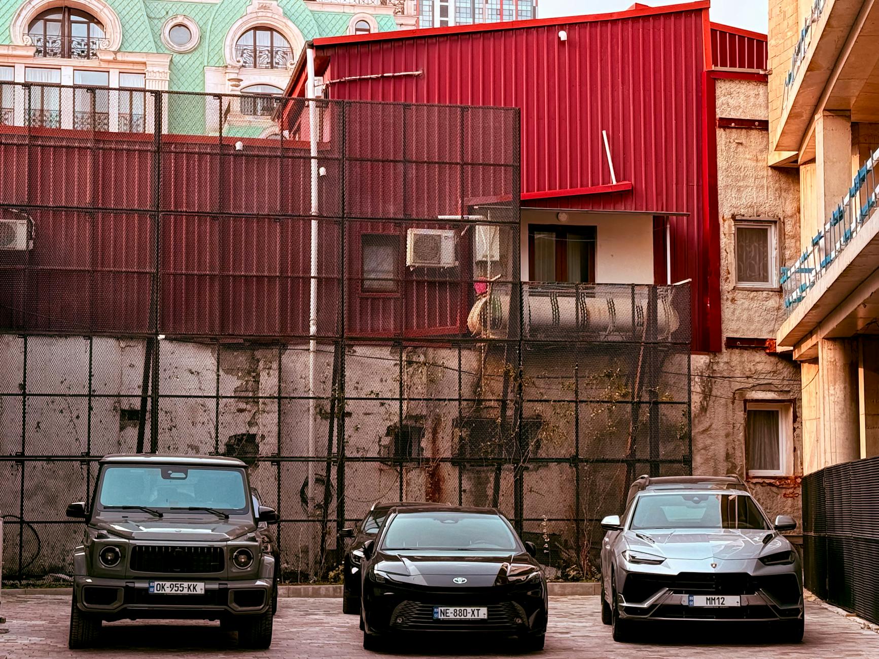 Które roczniki Porsche Cayenne i Macan najlepiej trzymają cenę i są najmniej problematyczne w serwisie Trzy miejskie samochody zaparkowane przed czerwonym budynkiem