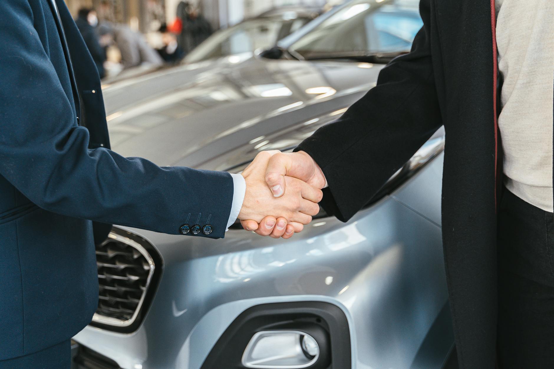 Uścisk dłoni kupującego z handlarzem przy samochodzie Renault w komisie