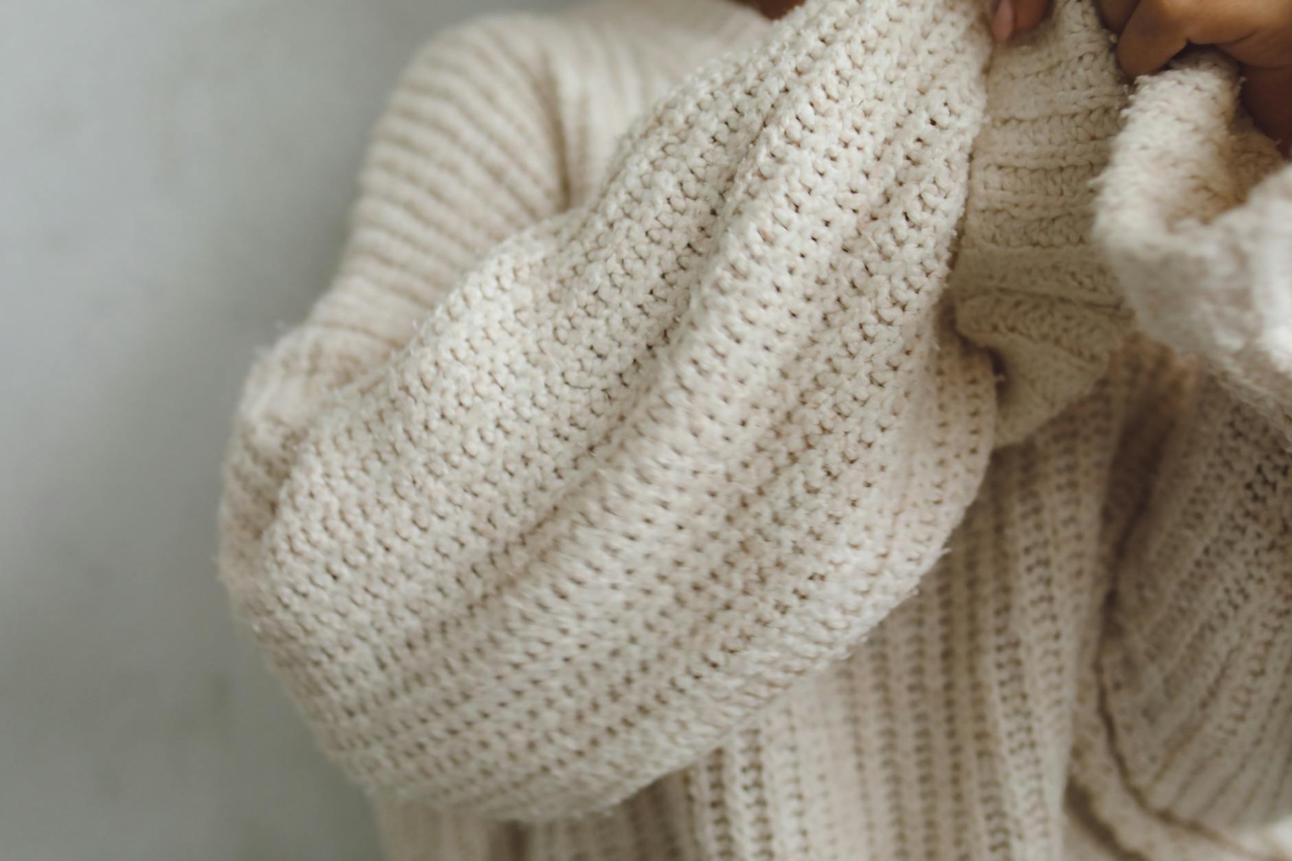 Beżowy, miękki sweter oversize w zbliżeniu, dzianinowy splot
