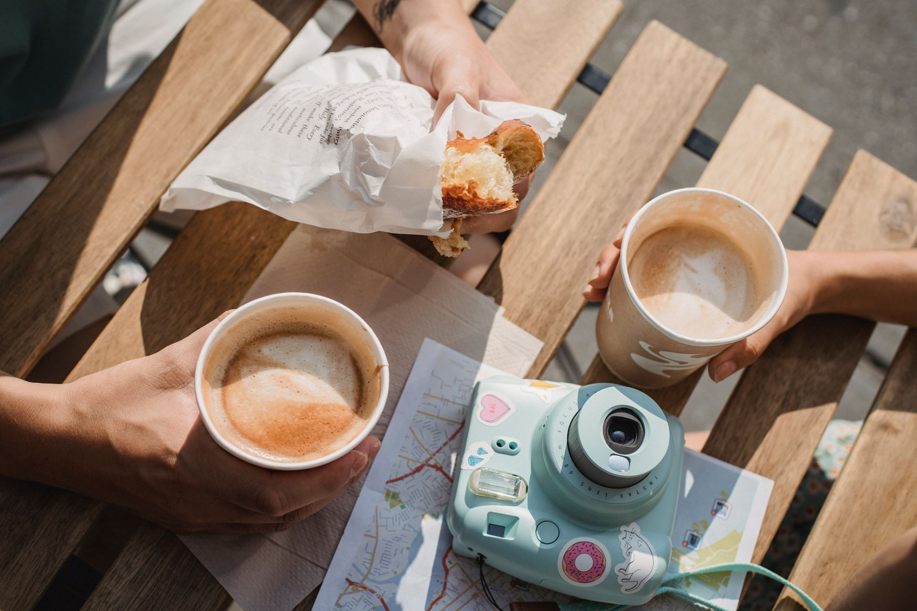 Para przy stoliku w kawiarni pije cappuccino, obok leży aparat fotograficzny