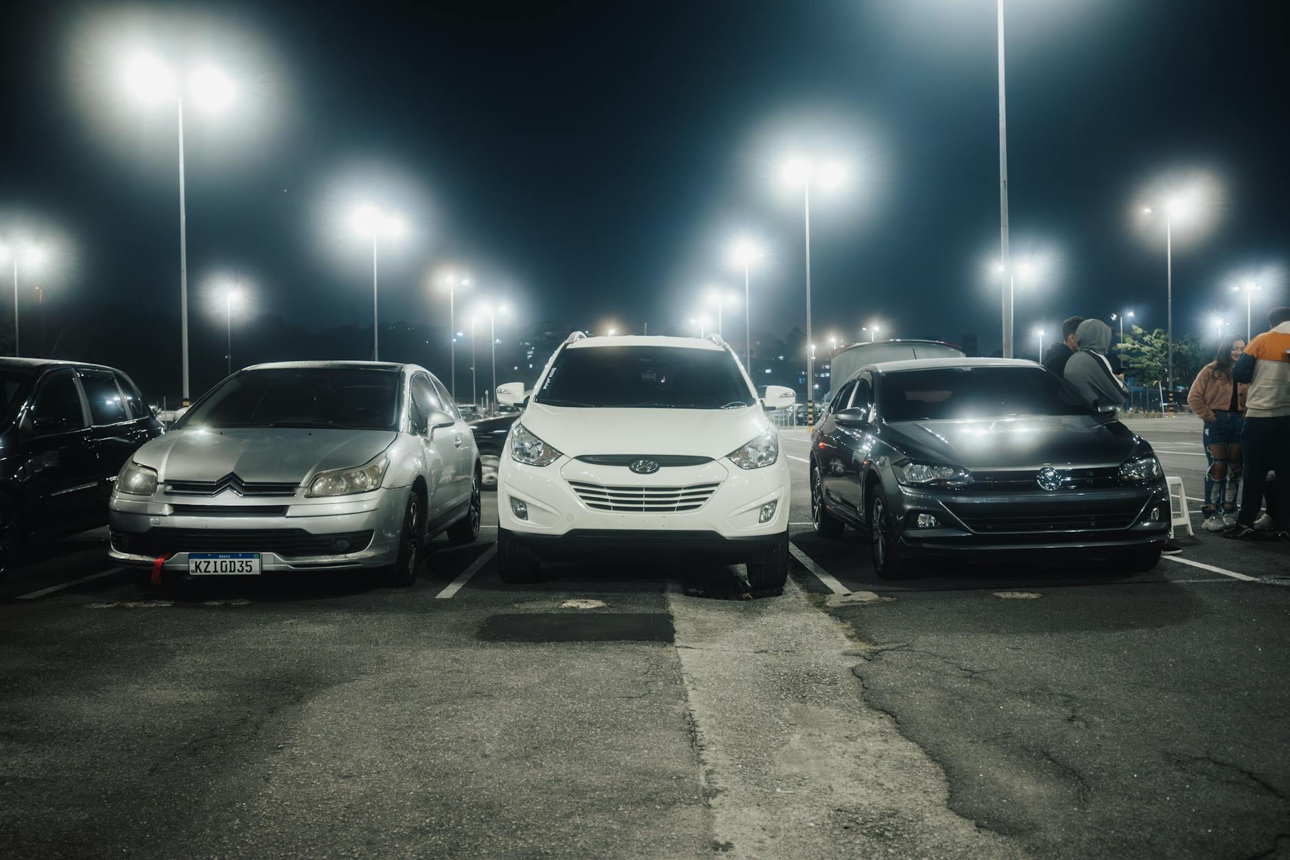 Samochody na nocnym, oświetlonym parkingu przy ulicznych latarniach