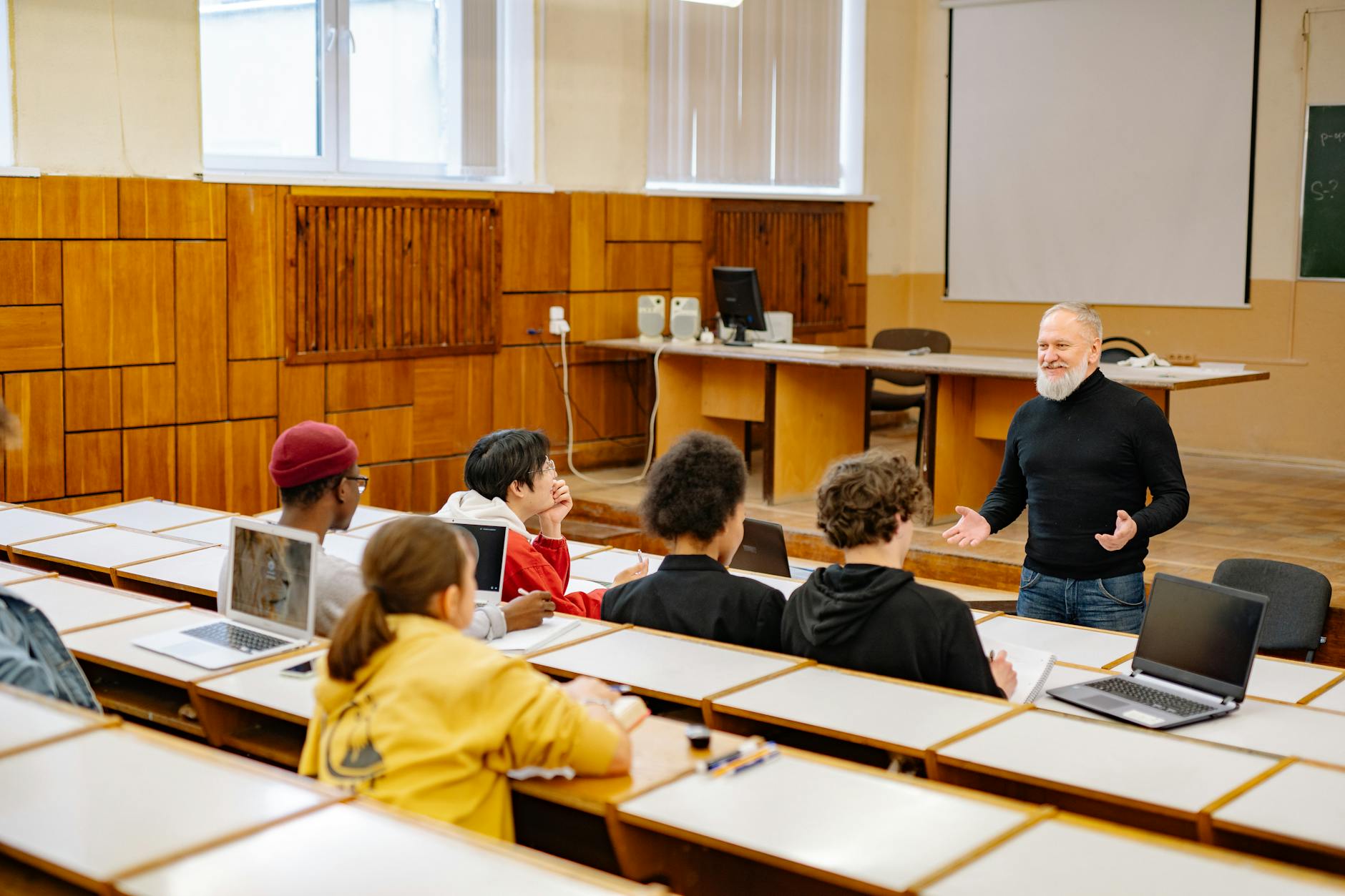 Jak projektować etyczne narzędzia AI w edukacji: praktyczne wskazówki dla szkół i nauczycieli Studenci i wykładowca na uczelni korzystają z laptopów podczas zajęć