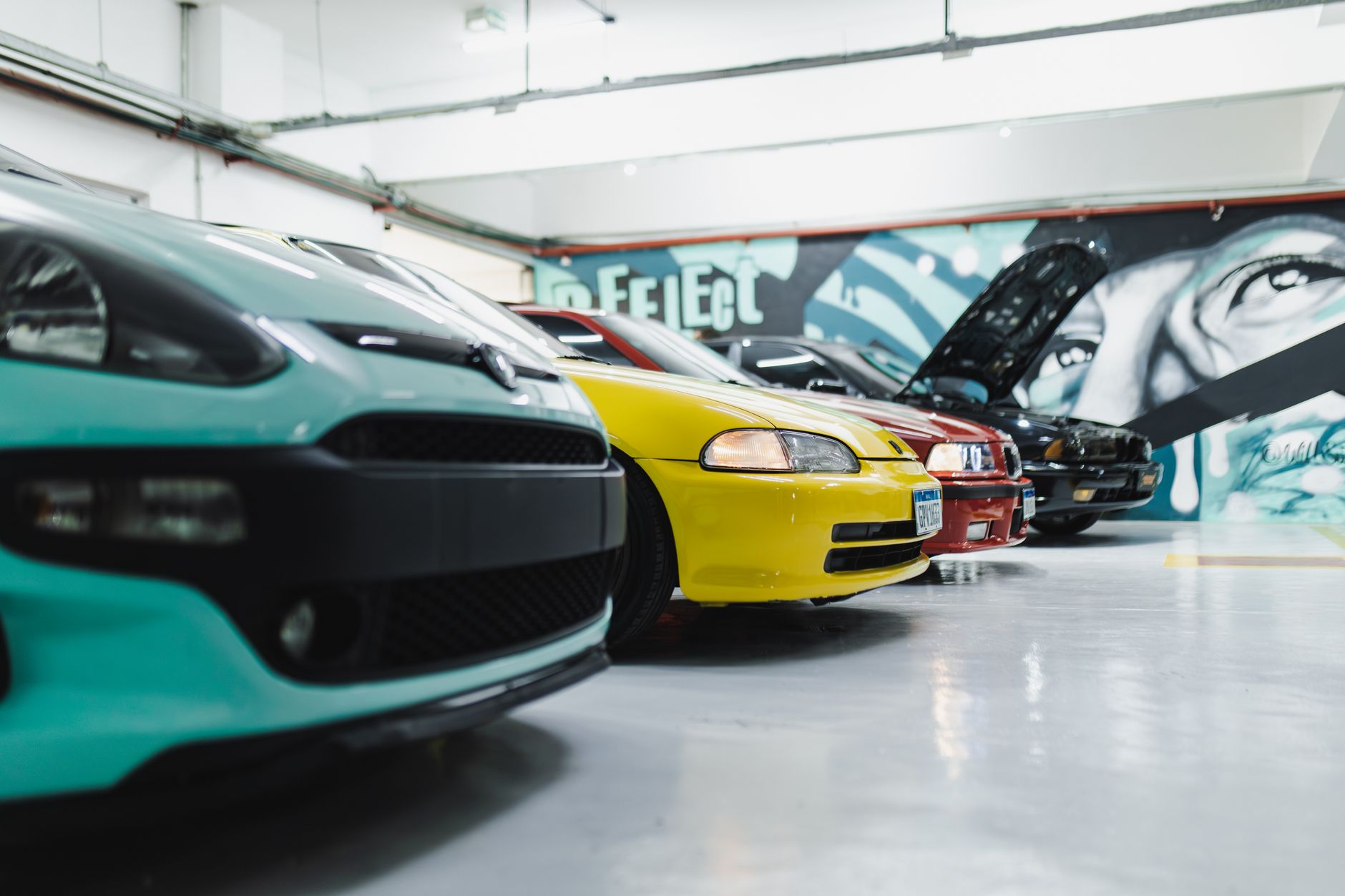 Tuningowane sportowe BMW w jasnym garażu z kolorowymi muralami