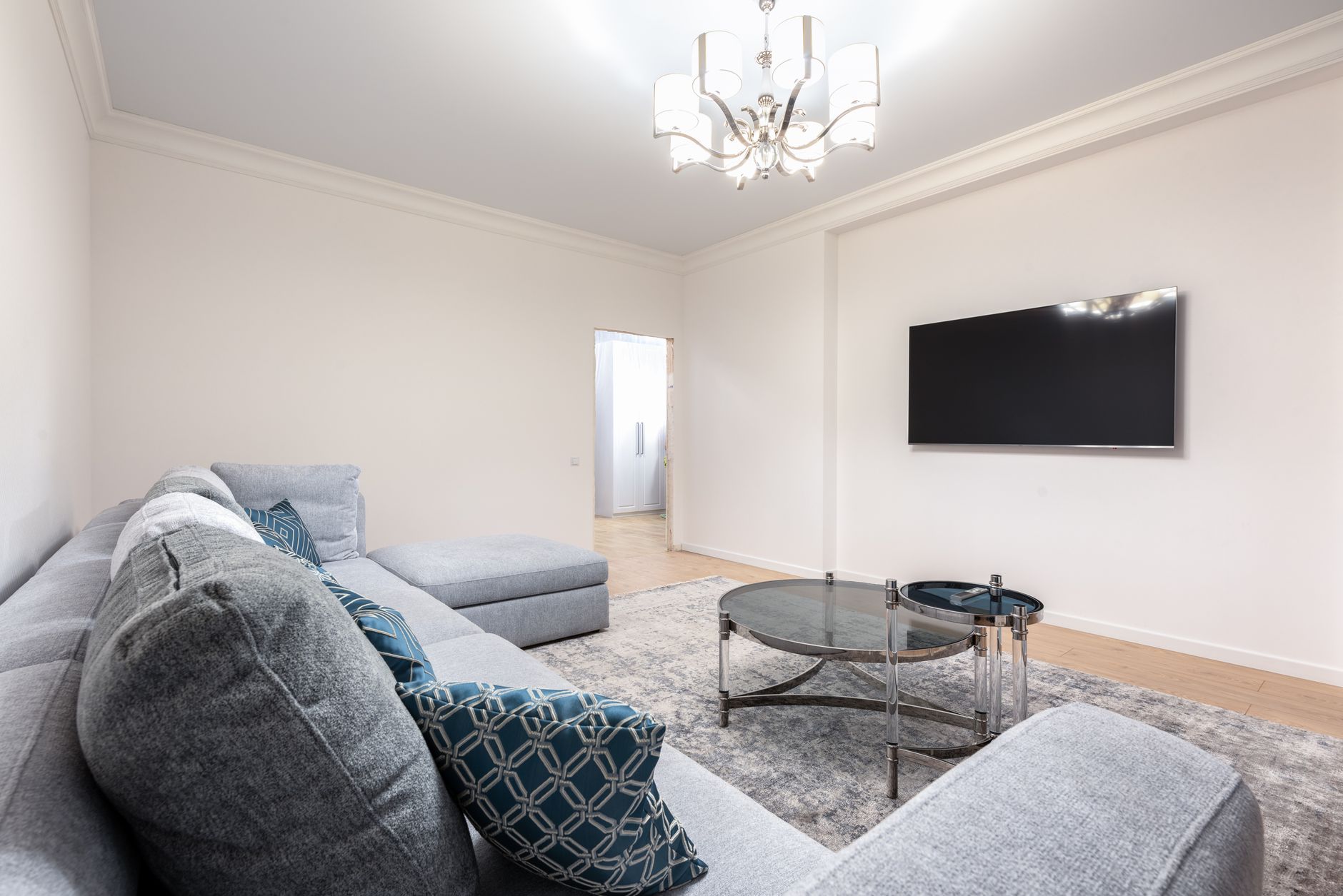 Nowoczesny salon z sofą, telewizorem i lśniącym żyrandolem